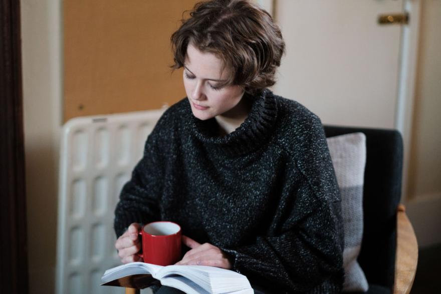 Student reading with a hot drink